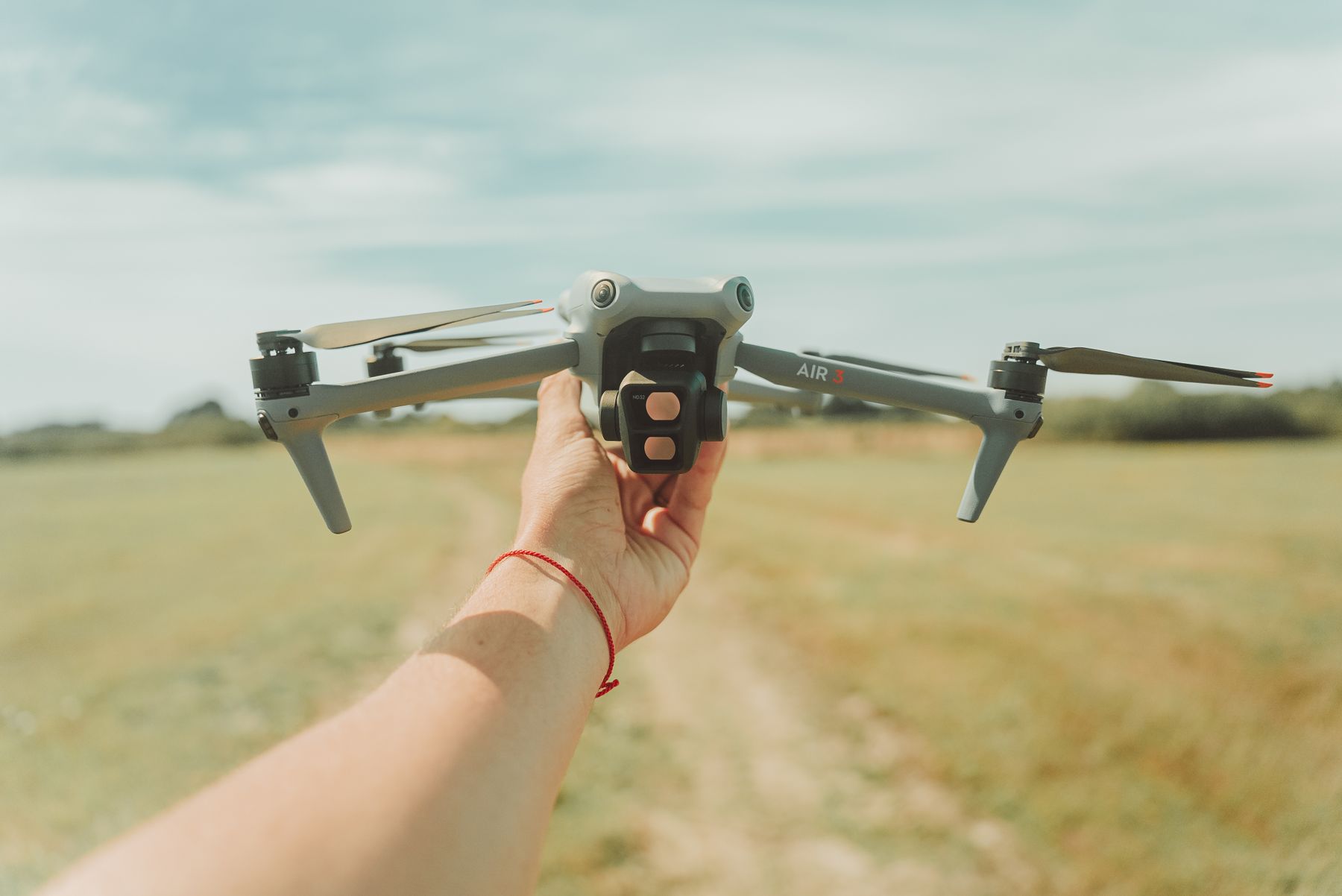 Professional operator holding a drone in an open field before flight